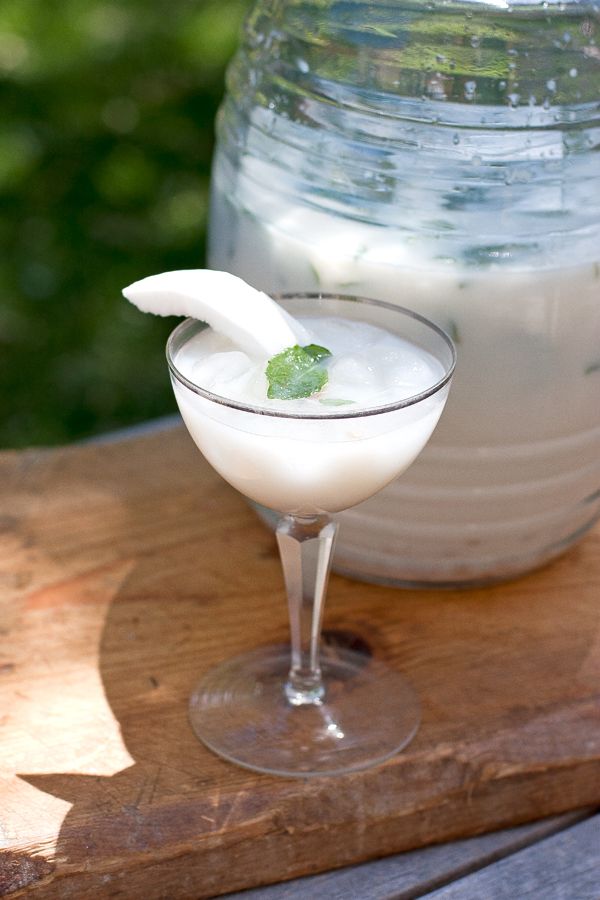 a drink in a glass sitting on top of a wooden table next to a jar