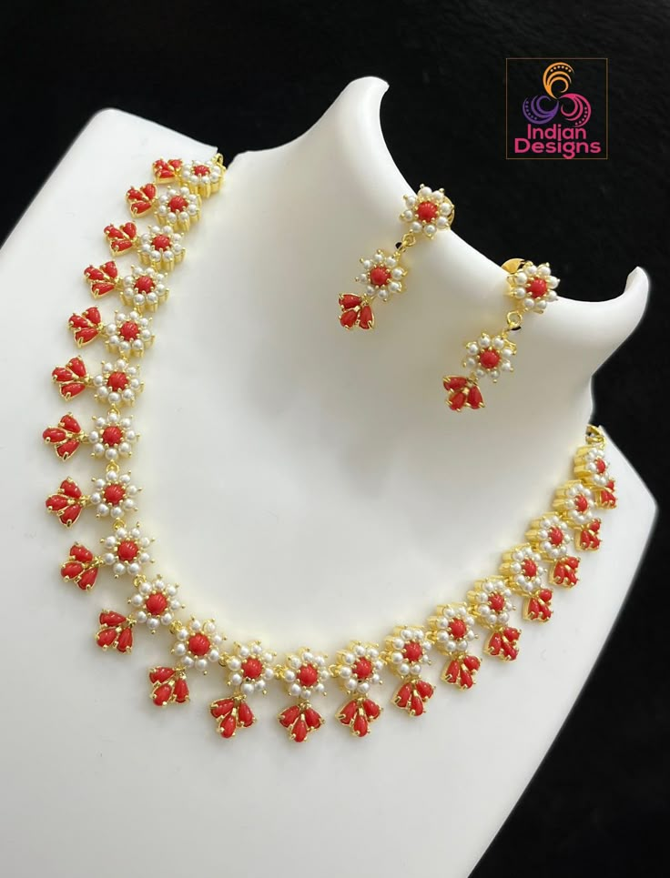 This traditional Gold Plated Exclusive Floral Motif Necklace boasts an exquisite design, with its pearls and red coral stones woven in an elegant flower pattern. Crafted with the finest Gold Plating and an intricate design, this piece is perfect for adding a touch of sophistication to any traditional saree. Carefully designed to make sure you stand out from the crowd. Coral Jewelry Design, Coral And Pearl Earrings, Pearl Coral Necklace, Coral Gold Necklace, Coral And Pearl Necklace, Kempulu Necklace, Gold Stone Necklace Designs, Antique Gold Jewelry Indian Necklaces, Coral Necklace Indian Gold