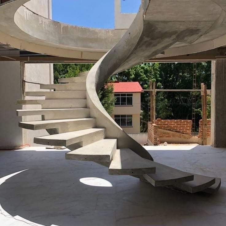 a spiral staircase in the middle of a building with concrete floors and steps leading up to it