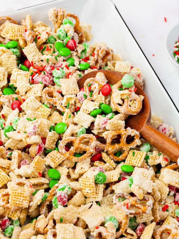 a bowl full of christmas cheer mix with a wooden spoon next to it on a table