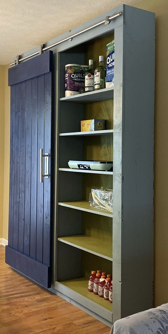 an open bookcase in the corner of a room with wood floors and blue doors