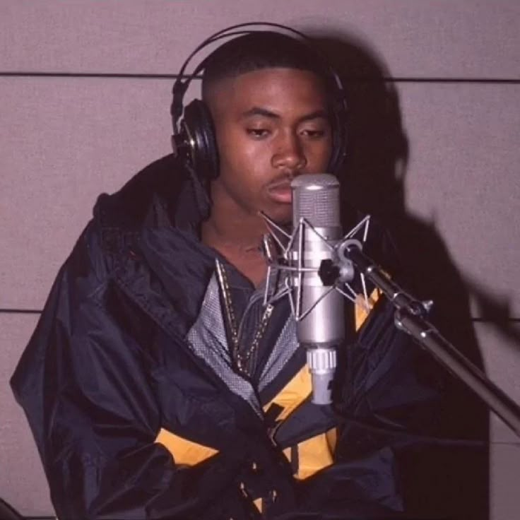 a young man wearing headphones and holding a microphone in front of a recording booth