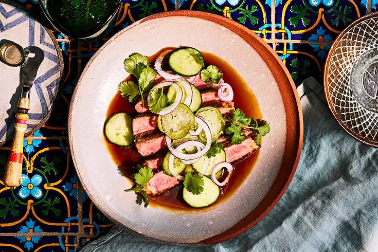 a bowl filled with meat and veggies on top of a blue table cloth