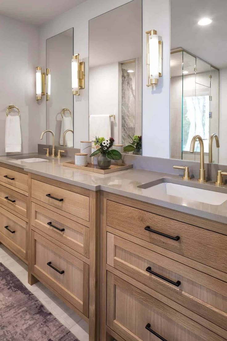 a bathroom with two sinks, mirrors and lights on the wall above them is shown