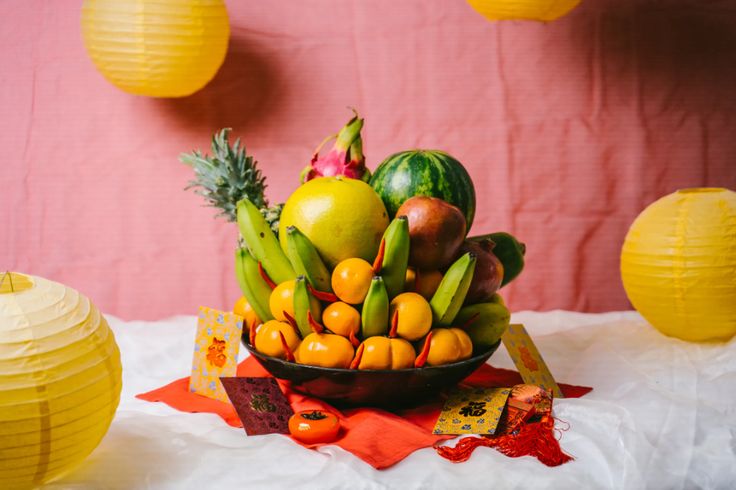 a bowl filled with lots of fruit sitting on top of a table next to paper lanterns