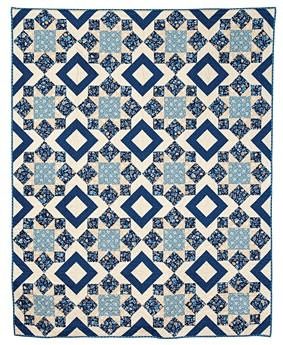 a blue and white quilt with diamond shapes on the front, in two different colors