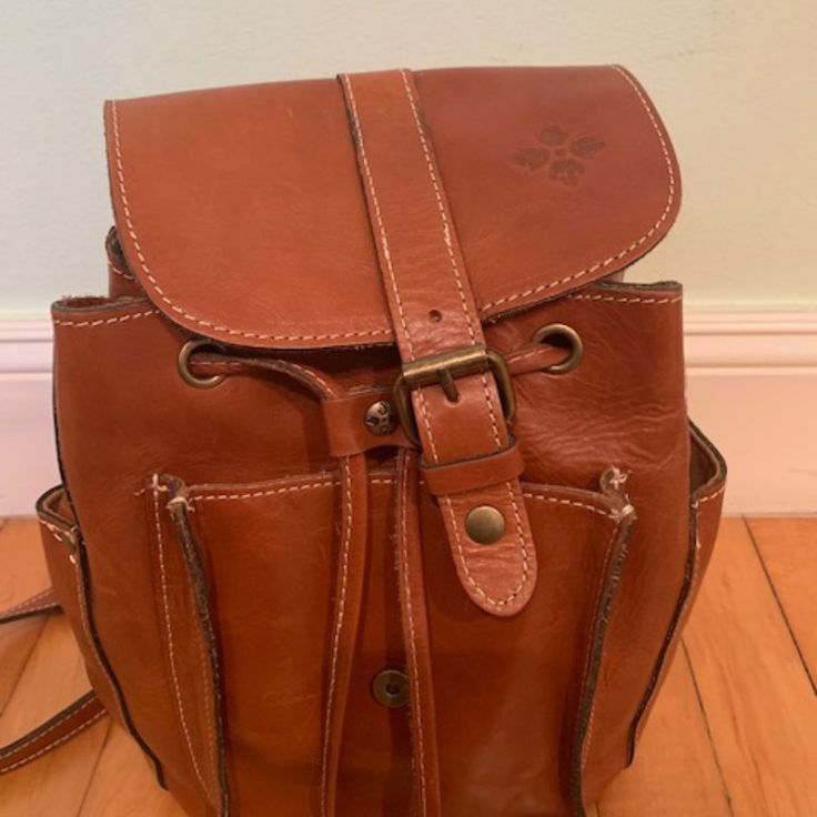 Great Condition. Lots Of Pockets. Hardly Used. Original Tags Available. Brown Distressed Italian Leather Bag Adjustable Shoulder Straps, Internal And External Pockets, Clasp Closure Interior: 1 Zip Pocket And 2 Slip Pockets, Lined Exterior: Front Flap With Buckle Detail, Front Pocket, 2 Slip Pockets On Sides Bag Measurements - H 10 X W 8 X B 5 Casual Brown Satchel With Leather Backing, Casual Brown Backpack With Removable Pouch, Casual Brown Leather Backpack With Leather Lining, Casual Brown Backpack With Leather Lining, Brown Bucket Backpack For Daily Use, Casual Backpack With Leather Lining, Brown Bucket Backpack For Everyday Use, Casual Cognac Satchel For Travel, Casual Leather Backpack For Errands