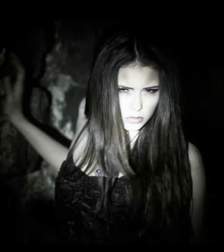 a woman with long hair standing in the dark