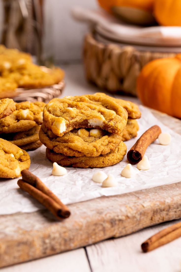 cookies with marshmallows and cinnamon are arranged on a cutting board next to pumpkins