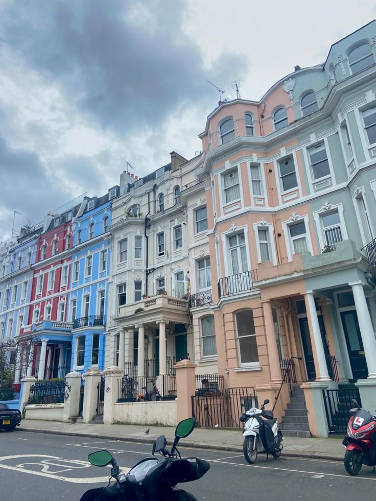 a row of multi - colored houses on the street with mopeds parked in front