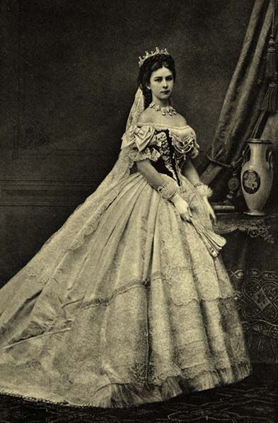 an old fashion photo of a woman in a wedding dress sitting on a table next to a mirror