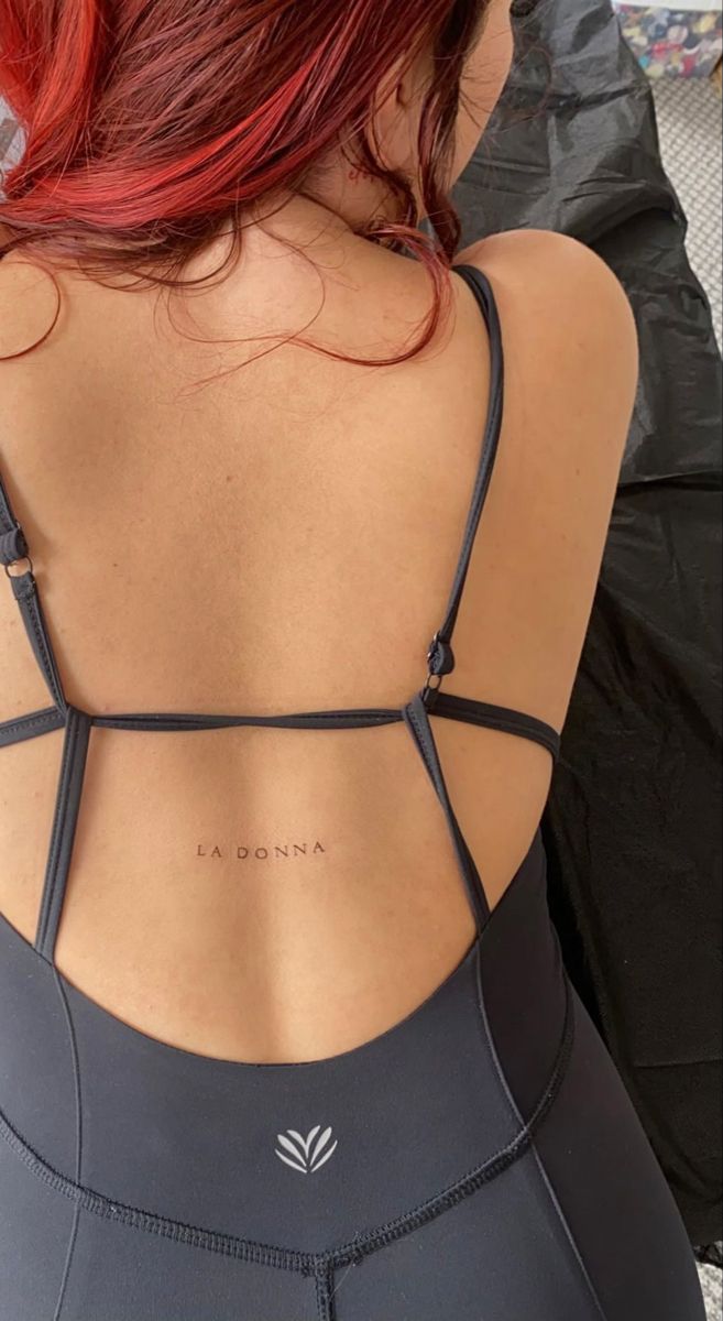 the back of a woman's sports bra with writing on her left shoulder and right arm