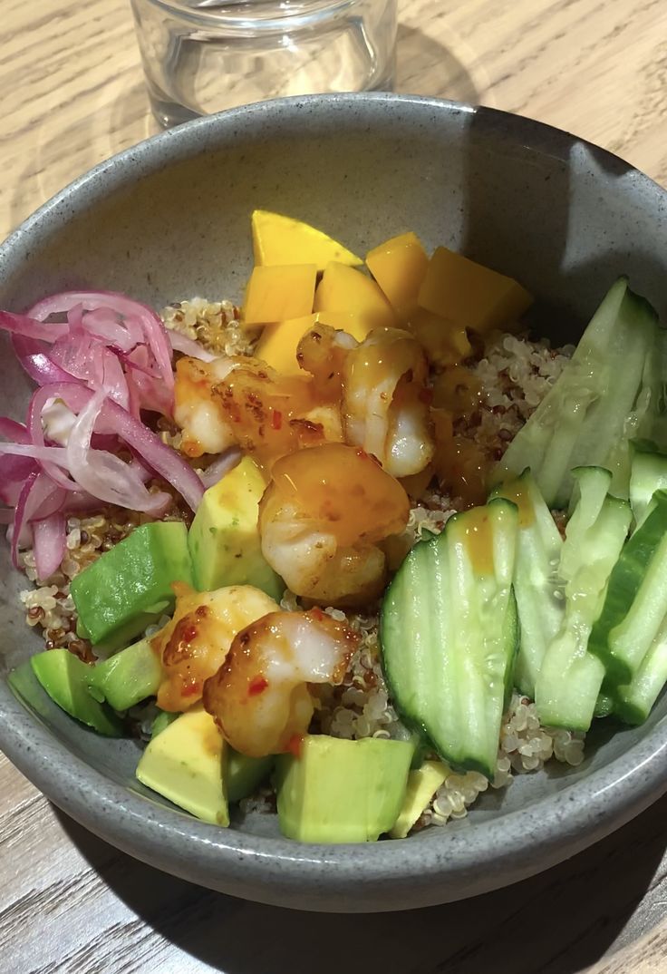 a bowl filled with shrimp and vegetables on top of a wooden table