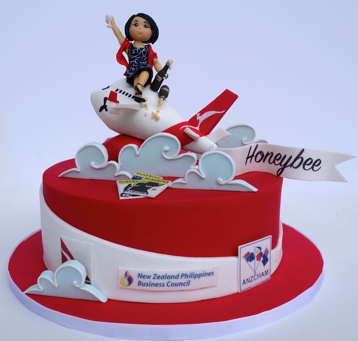 a red and white cake with a figurine sitting on top of the plane