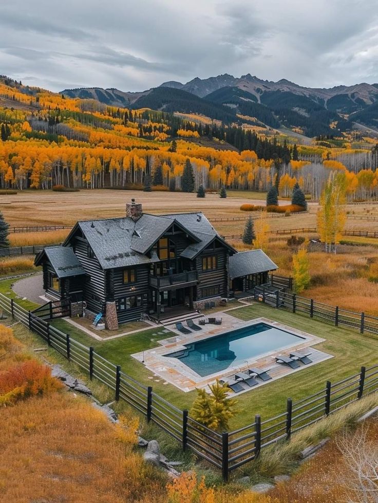 an aerial view of a large house with a pool in the foreground and mountains in the background