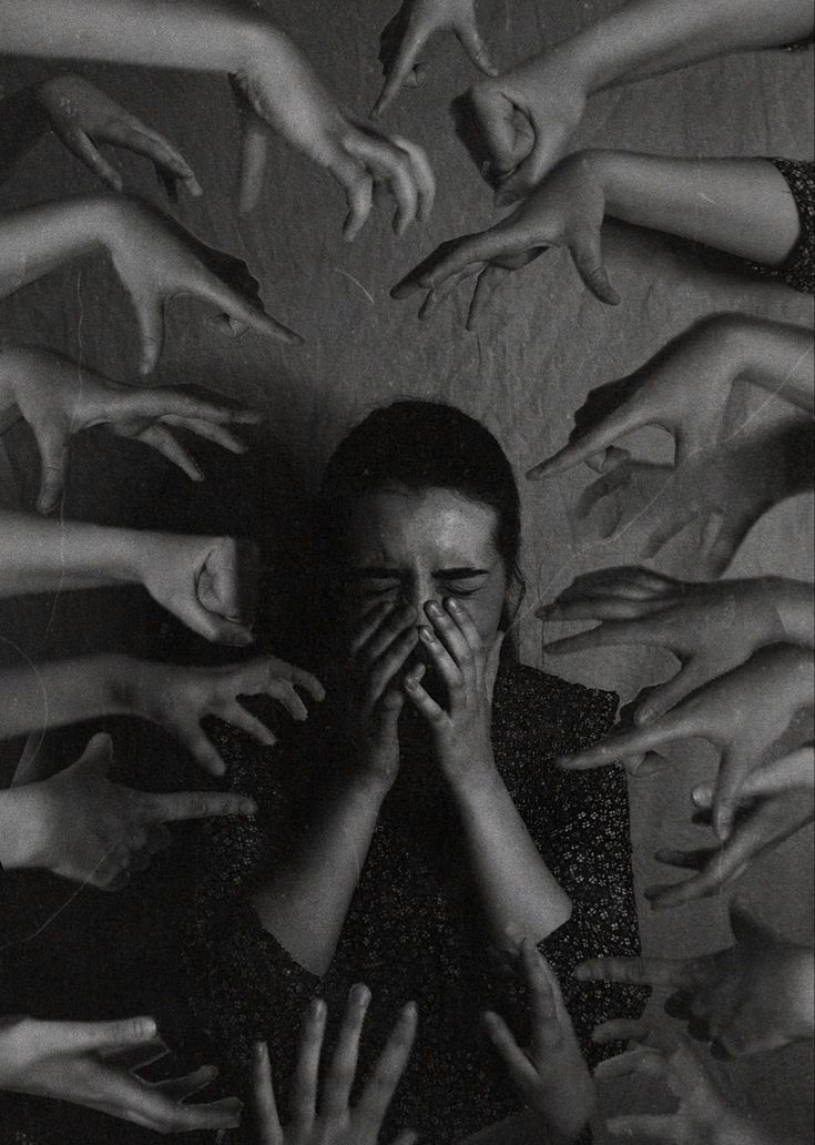 a woman covering her face surrounded by many hands