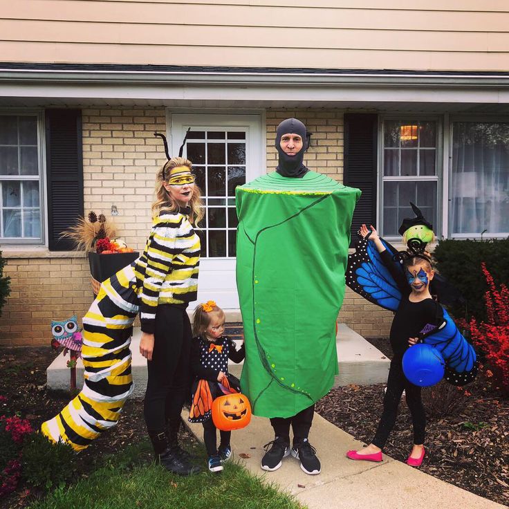 three people dressed up in costumes standing on the front lawn of a house with their children