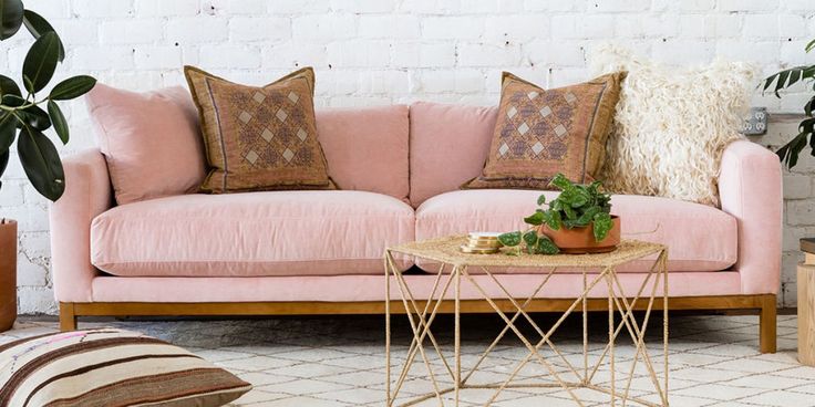 a living room with pink couches and potted plants on the side table in front of it