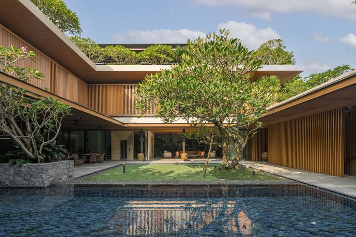 an outdoor swimming pool surrounded by wooden and glass walls, with trees in the background