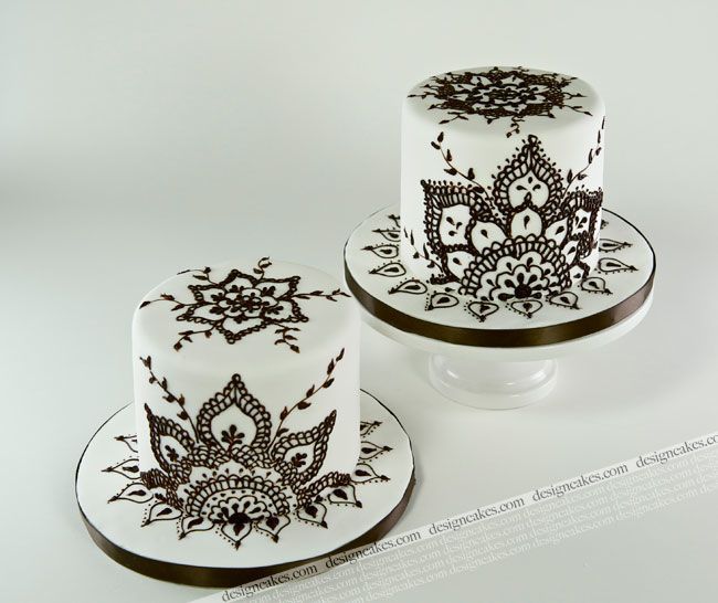 two white cakes with black designs on them sitting next to each other in front of a white background