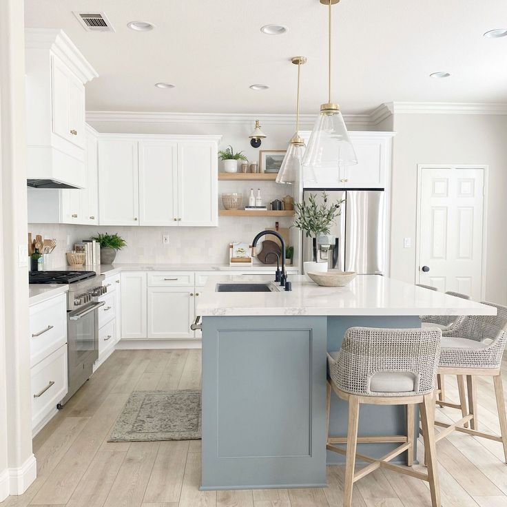 a kitchen with white cabinets and blue island in the center, surrounded by stools