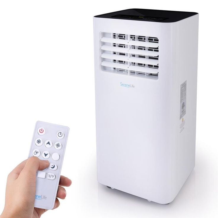 a person holding a remote control next to a small air conditioner