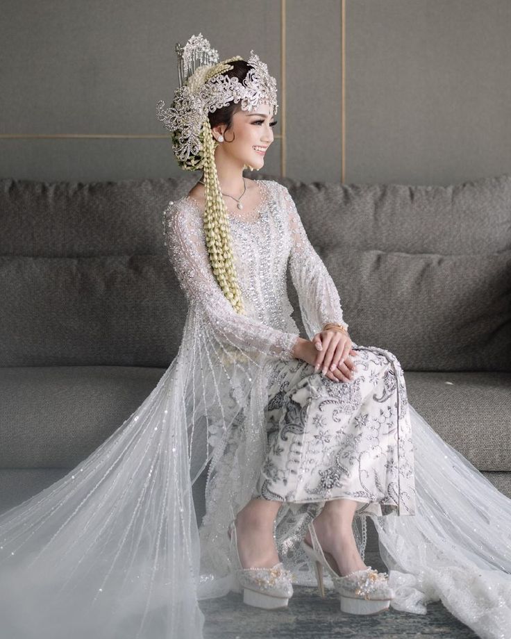 a woman sitting on top of a couch wearing a white dress and headdress