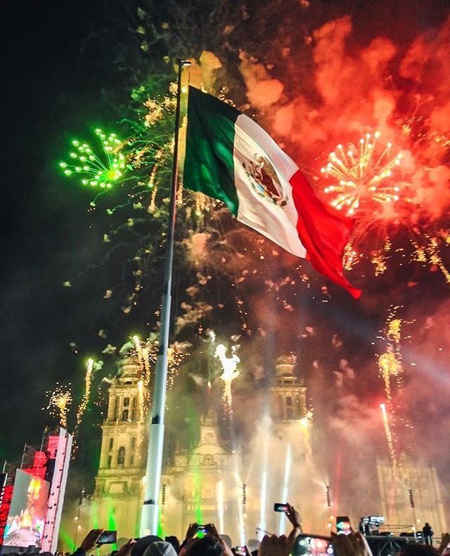 the mexican flag is flying in front of fireworks