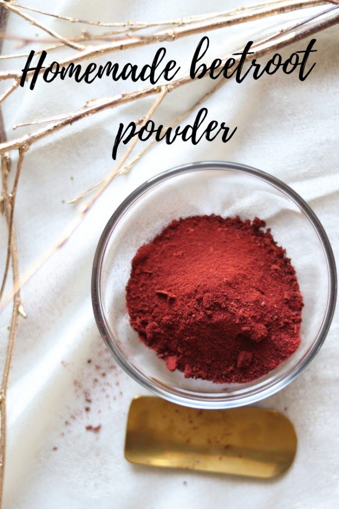 homemade beetroot powder in a glass bowl next to a golden spoon and twig