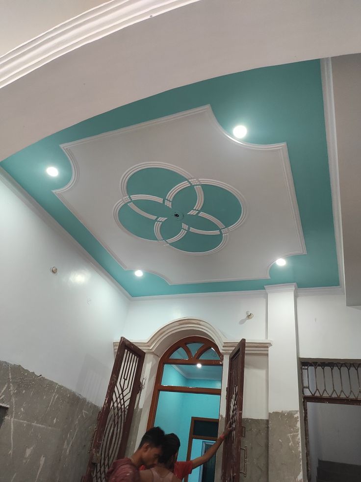 a woman standing in front of a doorway under a painted ceiling