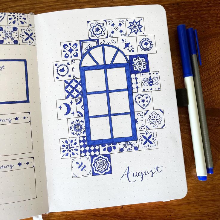 an open notebook with blue and white designs on the pages, next to a pen