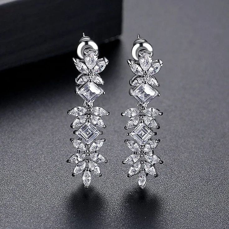 Be the epitome of elegance with our Denisse Earrings. These stunning luxury bridal earrings feature trendy cubic zirconia flowers that will make a statement on your special day. The hanging drop design adds a touch of sophistication to your bridal look. Perfect for engagement and a must-have for every fashion-forward bride. Metals Type: Copper Elegant Diamond White Flower Earrings For Wedding, Formal Dangle Flower Earrings With Cubic Zirconia, Cubic Zirconia Flower Earrings For Wedding, Luxury Diamond White Flower Earrings For Wedding, Luxury Cubic Zirconia Cluster Earrings For Wedding, Elegant Diamond Flower Earrings For Wedding, Elegant Flower Earrings With Sparkling Stones For Wedding, Luxury Drop Flower Earrings For Wedding, Luxury Flower Drop Earrings For Wedding