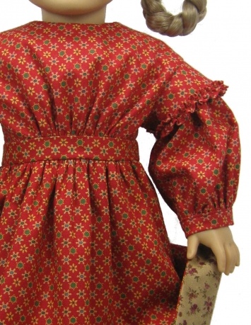 the doll is wearing a red dress with flowers on it