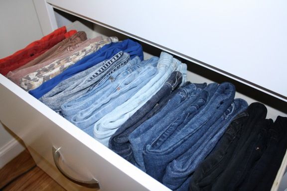 an open drawer with several pairs of jeans in it