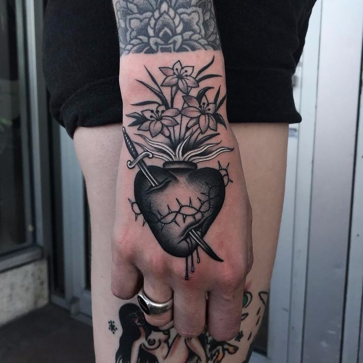 a person with a tattoo on their arm holding a heart and flowers in the shape of a book