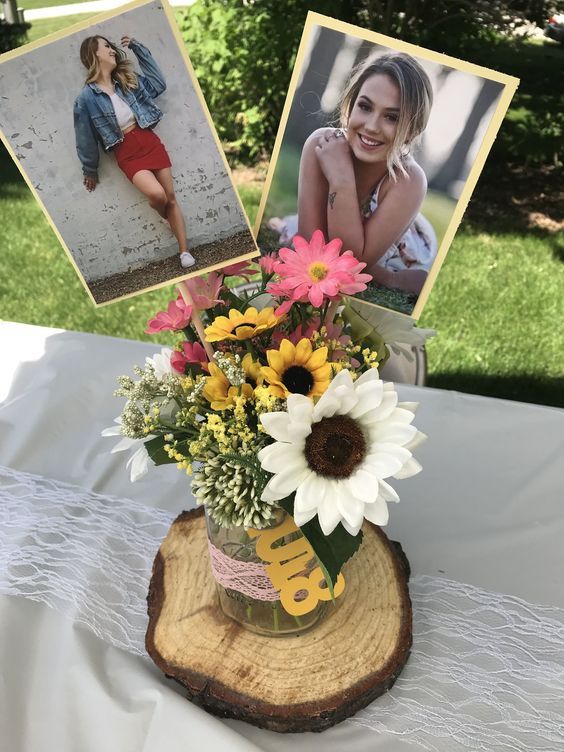 a vase filled with flowers sitting on top of a wooden table next to two pictures