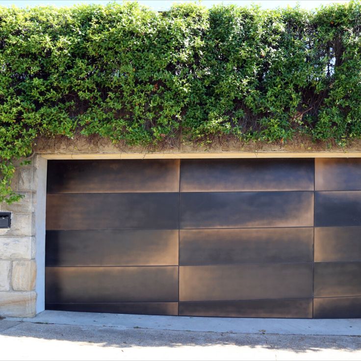 a large metal garage door in front of a brick wall with ivy growing on it