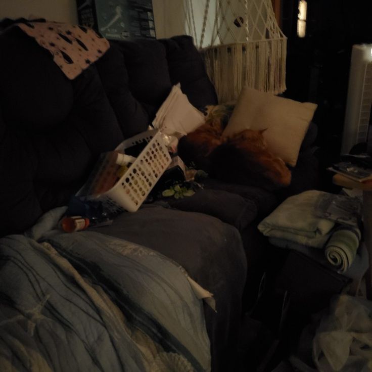 a messy living room with a couch and television remote control on it's arm