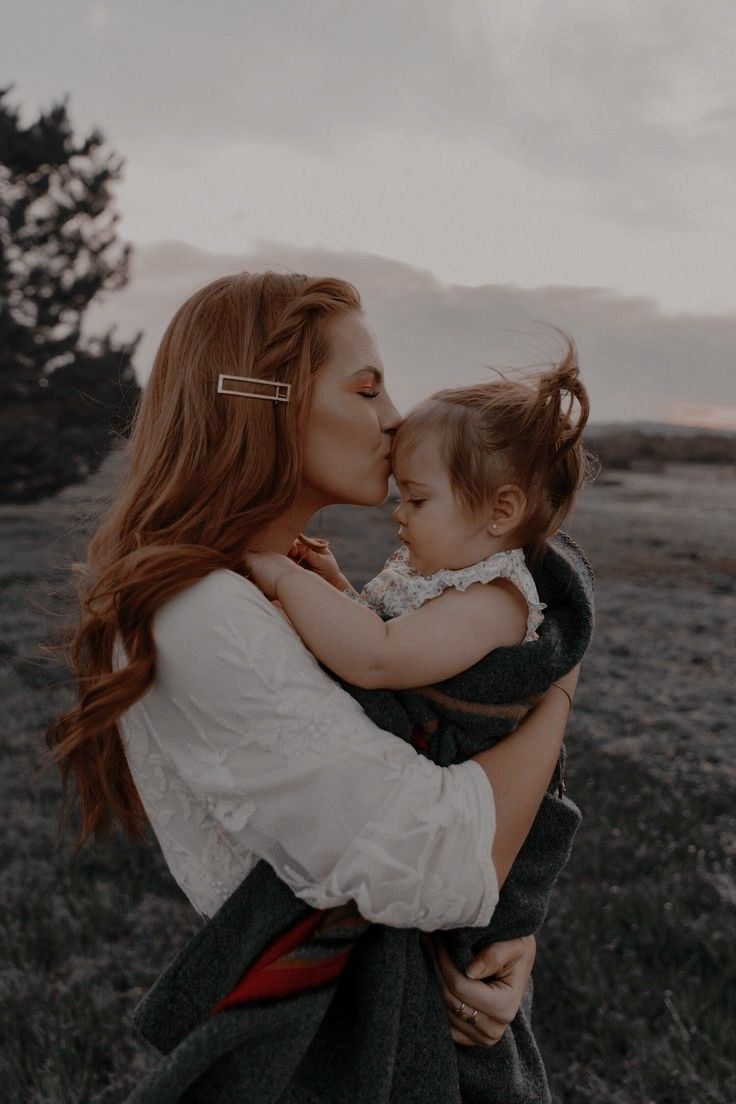 a woman holding a baby in her arms and kissing it's face on the cheek