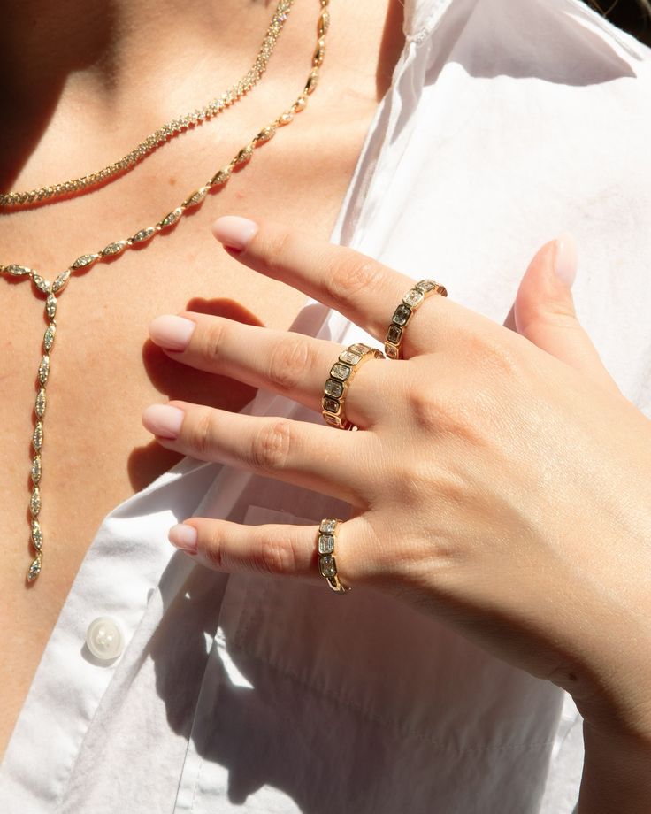 a woman wearing three different rings on her left hand and two necklaces on her right