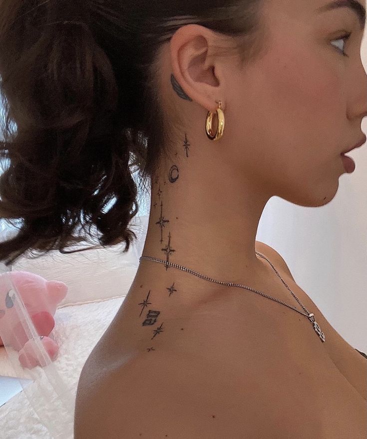 a woman with a cross tattoo on her neck and behind her ear is a teddy bear