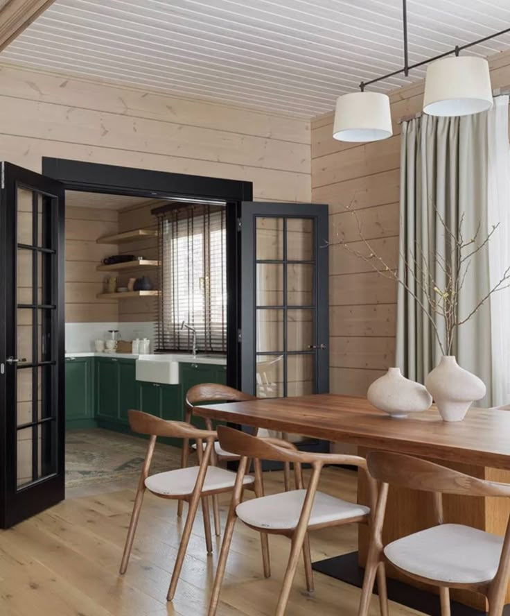 a dining room table with chairs and vases on it in front of the door