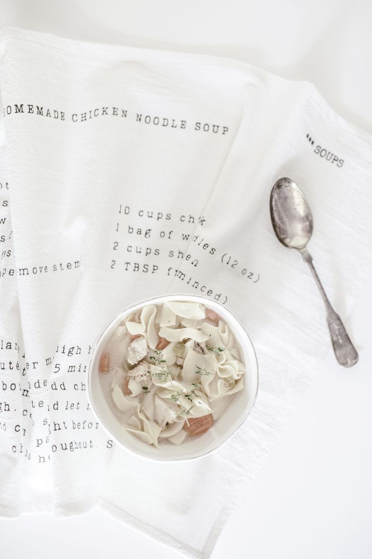 a bowl of food sitting on top of a table next to two napkins and a spoon