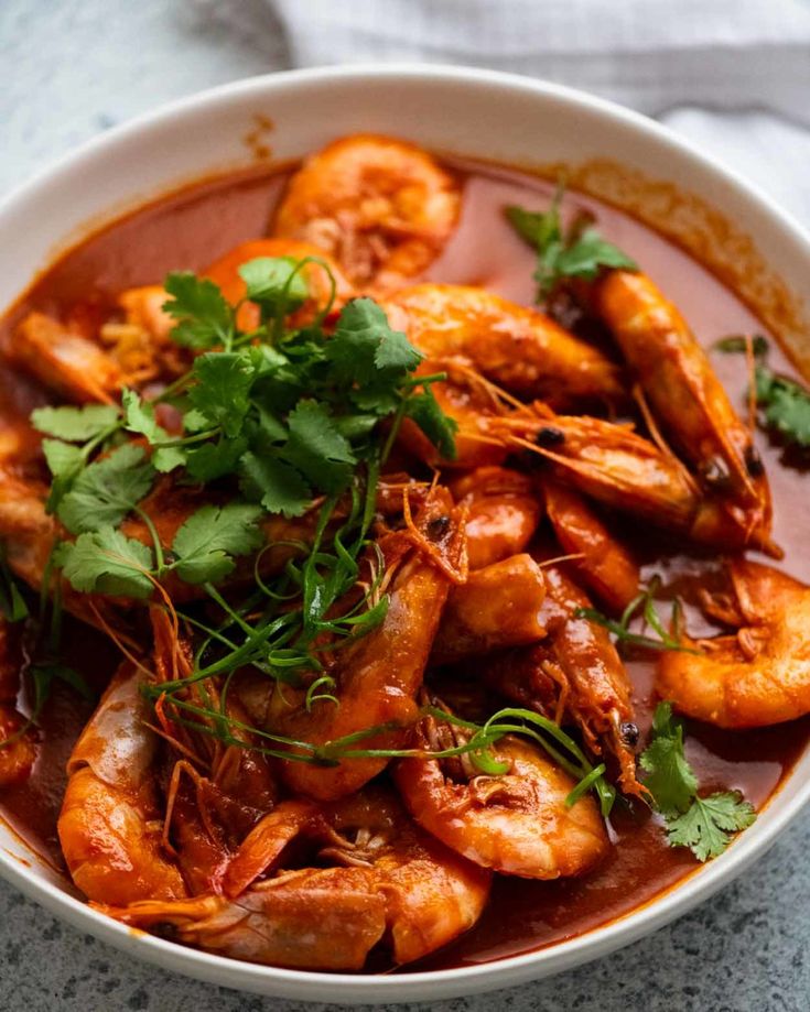 a white bowl filled with shrimp and garnished with cilantro