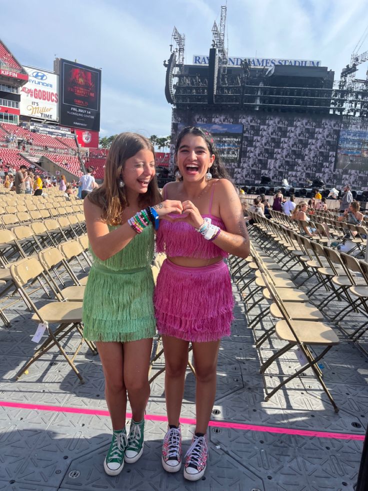 two girls standing next to each other at a baseball game