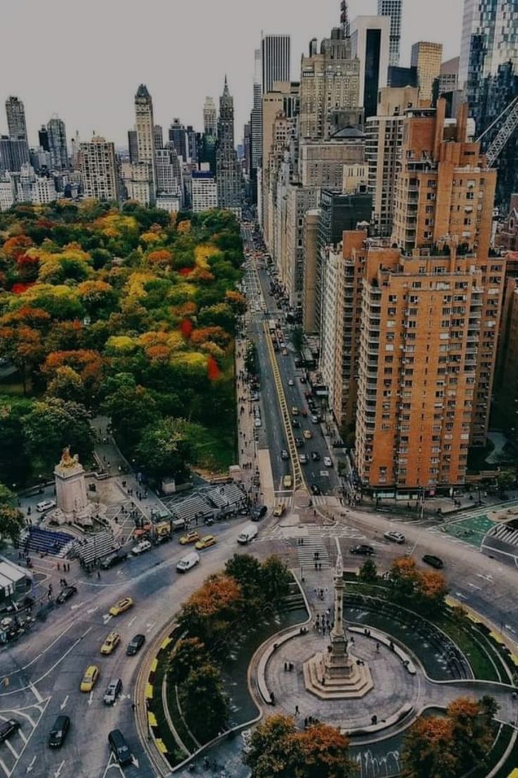 an aerial view of a city with lots of tall buildings and trees in the foreground