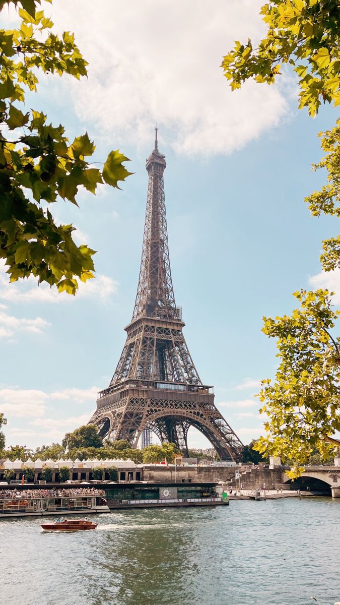 the eiffel tower is surrounded by trees and boats on the river below it