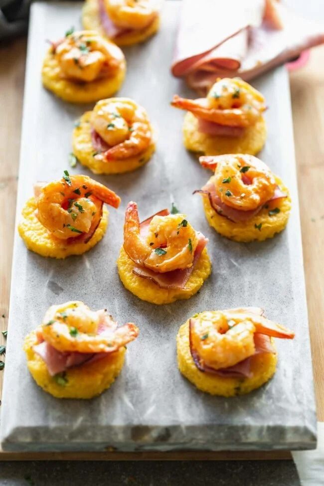 small crackers with shrimp and cheese are on a baking sheet, ready to be eaten