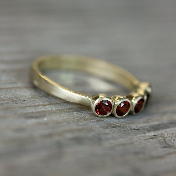 Five glistening crimson Red garnets are set into my hand carved setting. Each piece is solid 14k Yellow gold with bezel set 3mm stones. I make these in size 4-10, whole and half sizes.The bezel height is 4mm from the finger, so the profile is low and comfortable.garnet is the birthstone for Januaray and this ring is available in both raspberry pink Rhodolite Garnet and scarlet red garnet.Please let me know which you would prefer along with your size in the message to seller at checkout. Round Garnet Jewelry Stamped 14k, Heirloom Garnet Ring With Bezel Setting, Heirloom Garnet Jewelry With Bezel Setting, Heirloom Red Ring With Bezel Setting, Red Stackable Rings With Bezel Setting As Gift, Red Jewelry With Bezel Setting For Anniversary, Anniversary Stackable Garnet Jewelry, Garnet Bezel Set Ring Jewelry, Three Stone Garnet Jewelry For Anniversary