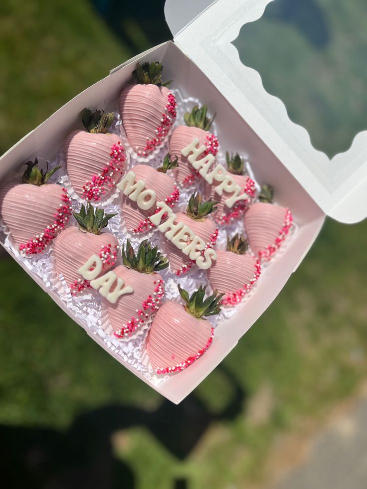 a box filled with pink strawberries sitting on top of a green field